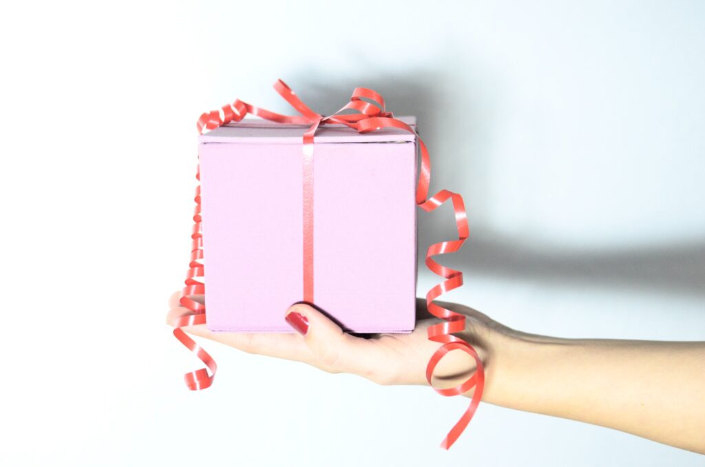 woman holding gift in a soft pink box with a red ribbon
